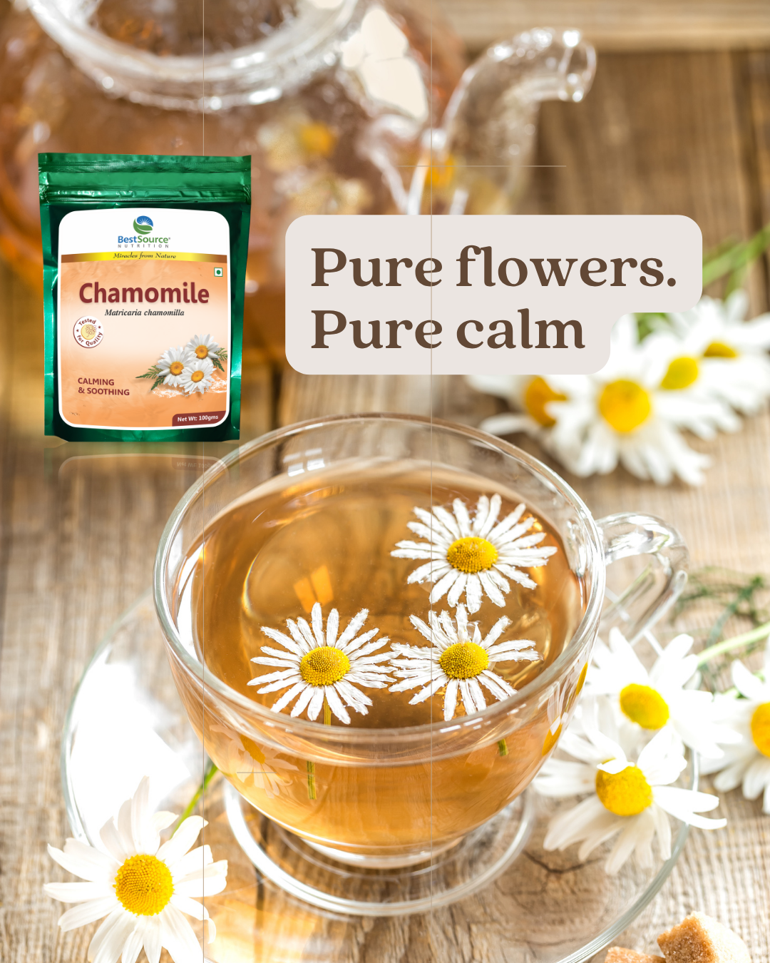 A glass teacup filled with chamomile tea sits on a saucer surrounded by chamomile flowers on a wooden surface. A small package of chamomile tea is shown in the upper left, with the text 'Pure flowers.